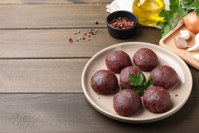 Many fresh raw meatballs on wooden table, space for text