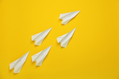 Many white handmade paper planes on yellow background. Space for text