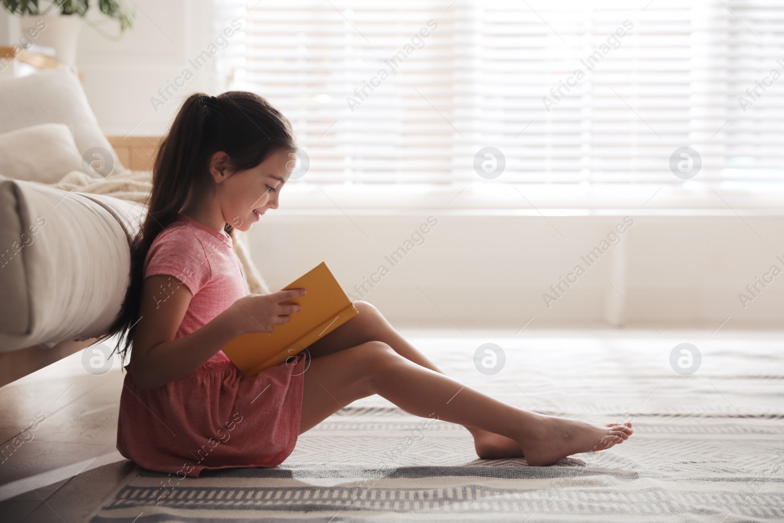 Photo of Little girl reading fairy tale in living room