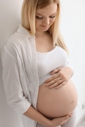 Photo of Portrait of beautiful pregnant woman near light wall