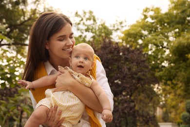 Photo of Happy mother with adorable baby walking in park on sunny day, space for text