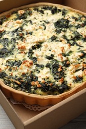 Photo of Delicious homemade spinach quiche in carton box, closeup