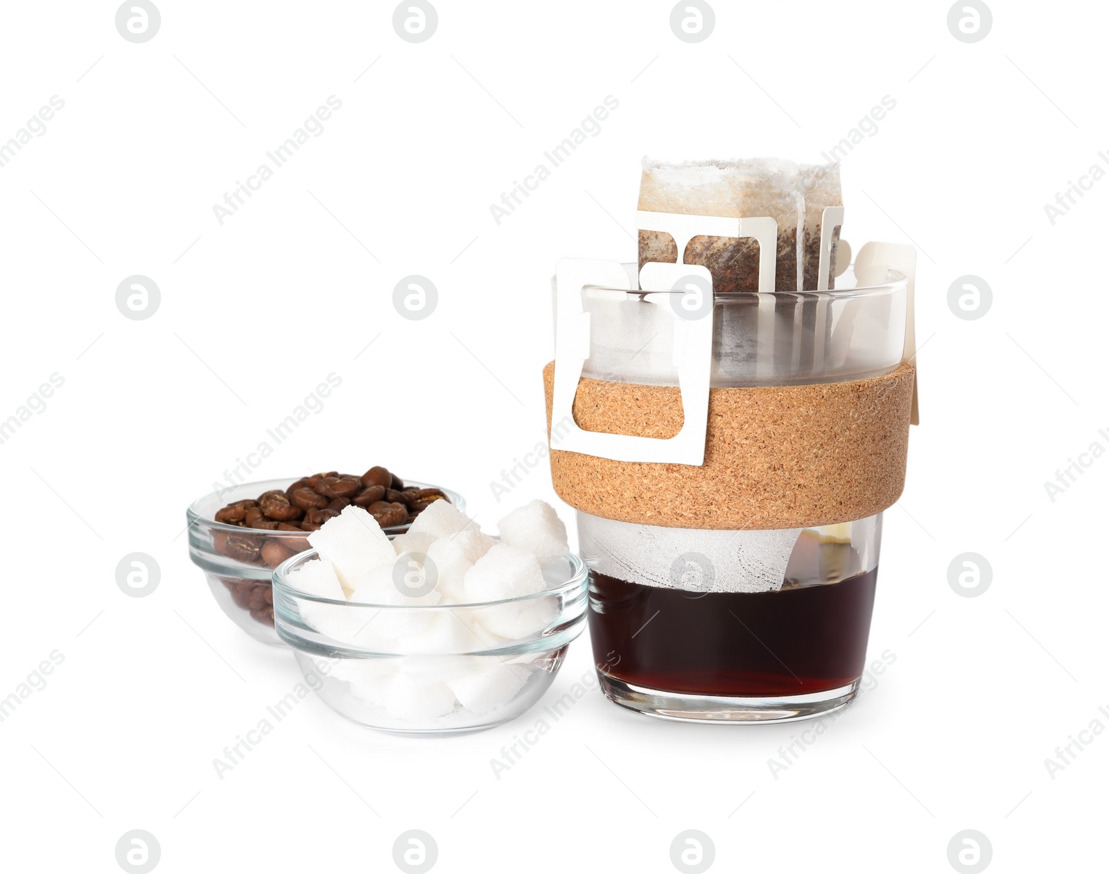 Photo of Glass cup with drip coffee bag, beans and sugar cubes isolated on white