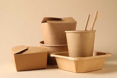 Photo of Eco friendly food packaging. Paper containers and tableware on beige background