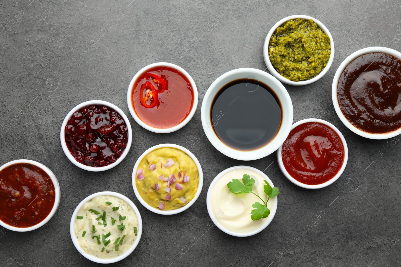 Photo of Different tasty sauces in bowls on grey table, flat lay
