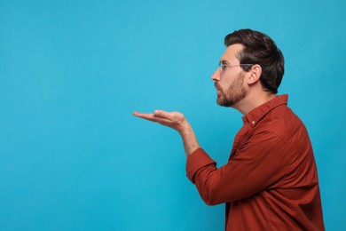 Photo of Handsome man blowing kiss on light blue background. Space for text