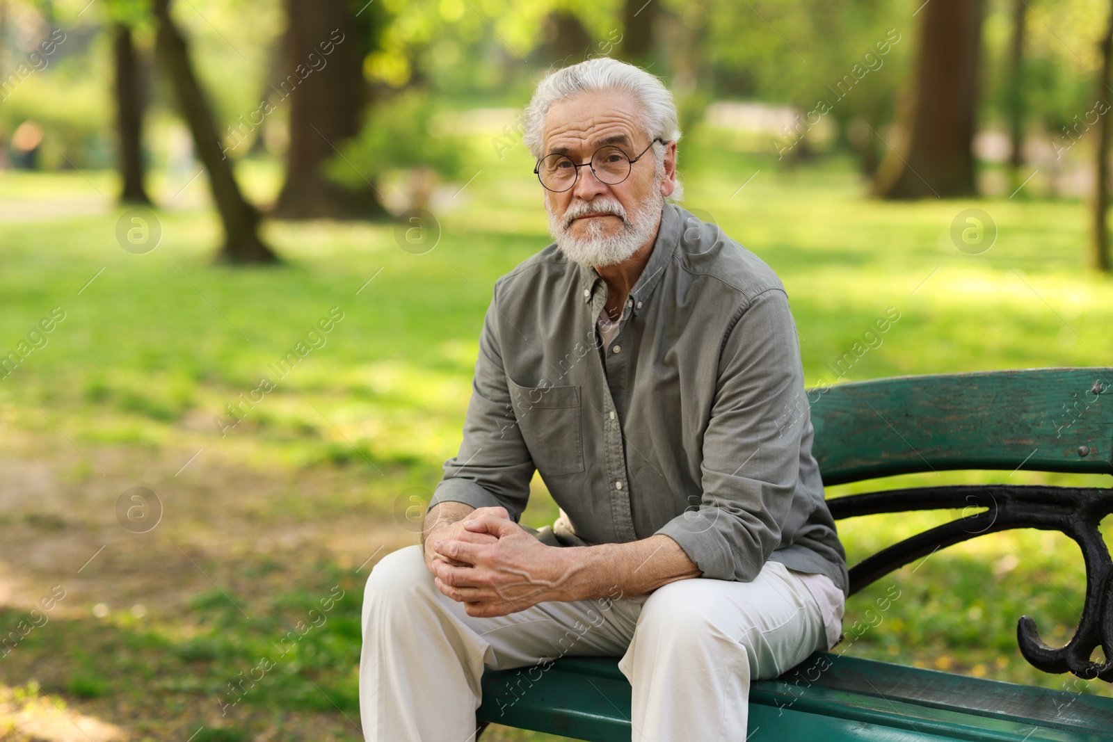 Photo of Portrait of happy grandpa with glasses on bench in park