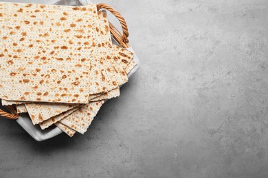 Photo of Traditional matzos in basket on light grey table, top view. Space for text