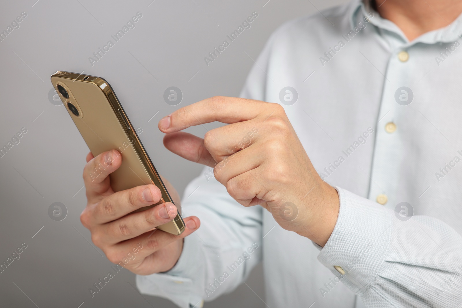 Photo of Man sending message via smartphone on grey background, closeup