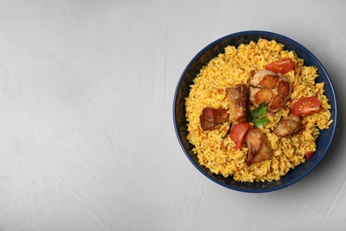 Photo of Bowl of delicious rice pilaf on grey background, top view with space for text