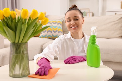 Photo of Spring cleaning. Young woman tidying up living room at home