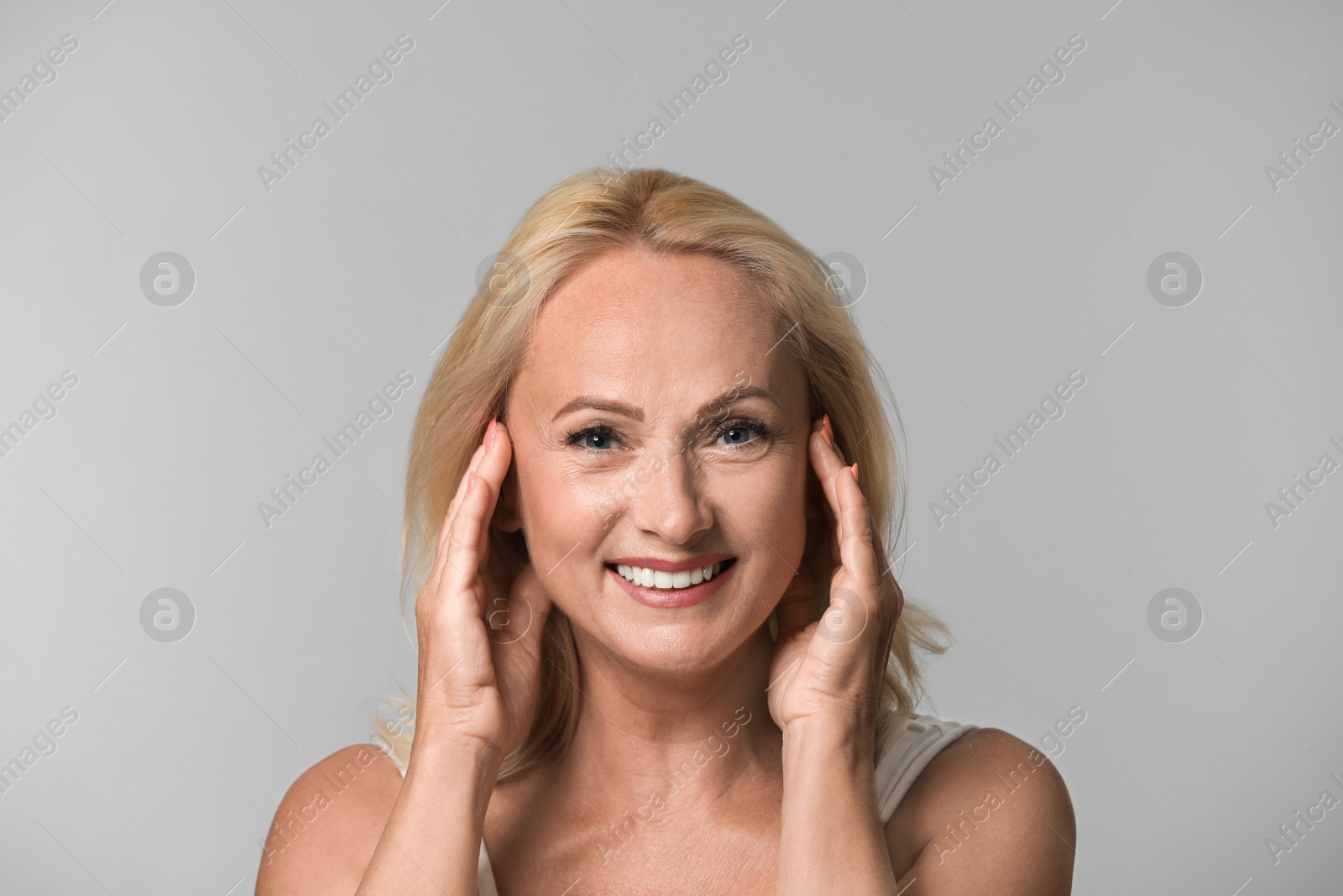 Photo of Portrait of beautiful mature woman with perfect skin on grey background