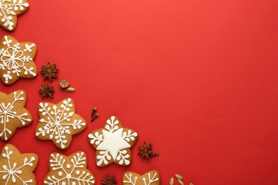 Photo of Tasty star shaped Christmas cookies with icing and spices on red background, flat lay. Space for text