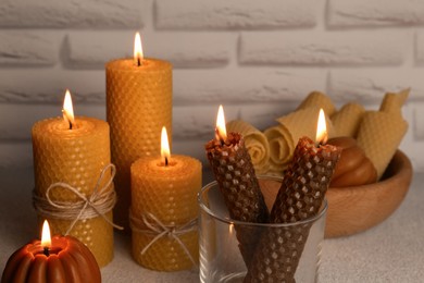 Photo of Beautiful burning beeswax candles on light textured table