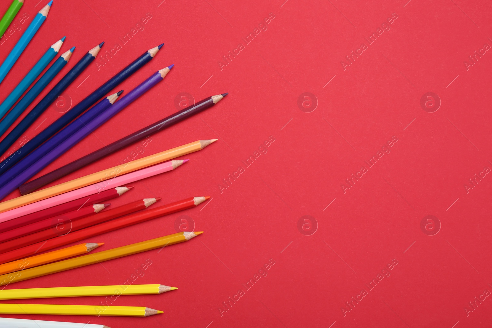 Photo of Colorful pencils on red background, flat lay. Space for text