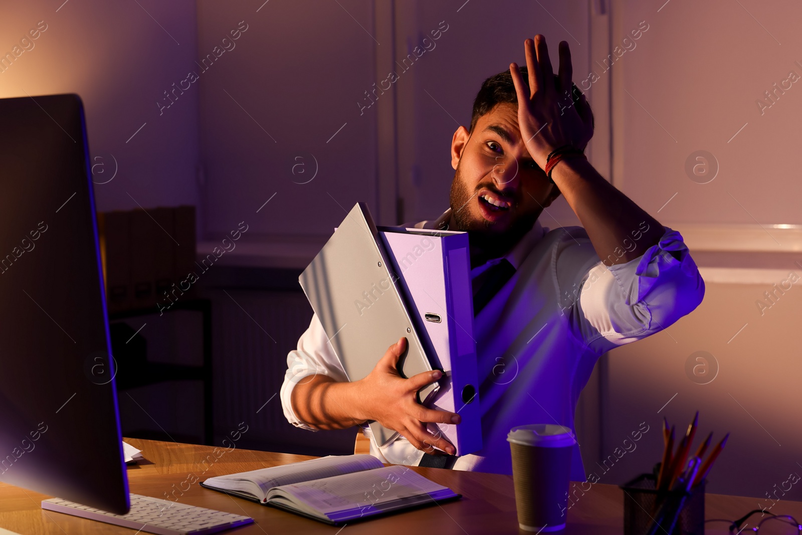 Photo of Tired young man working late in office