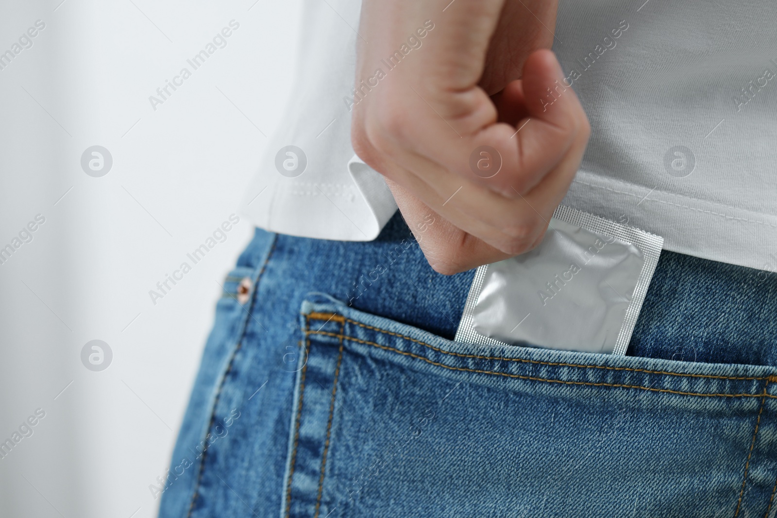 Photo of Man pulling condom out of pocket on blurred background, closeup. Space for text