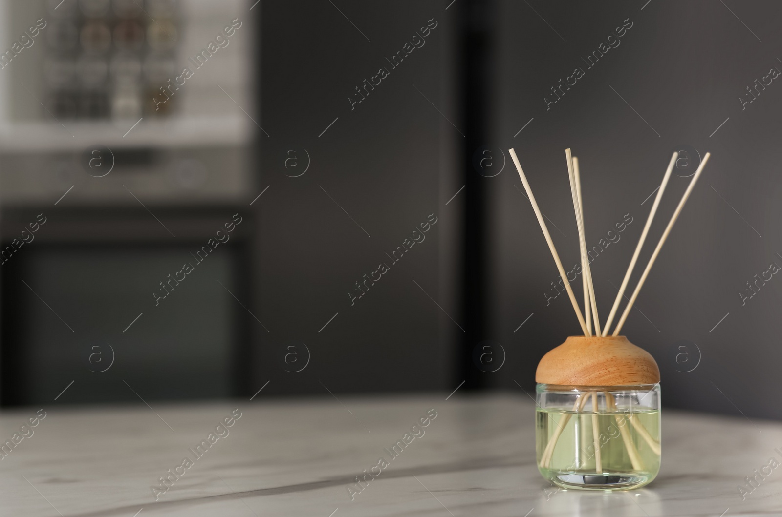 Photo of Aromatic reed air freshener on table indoors. Space for text