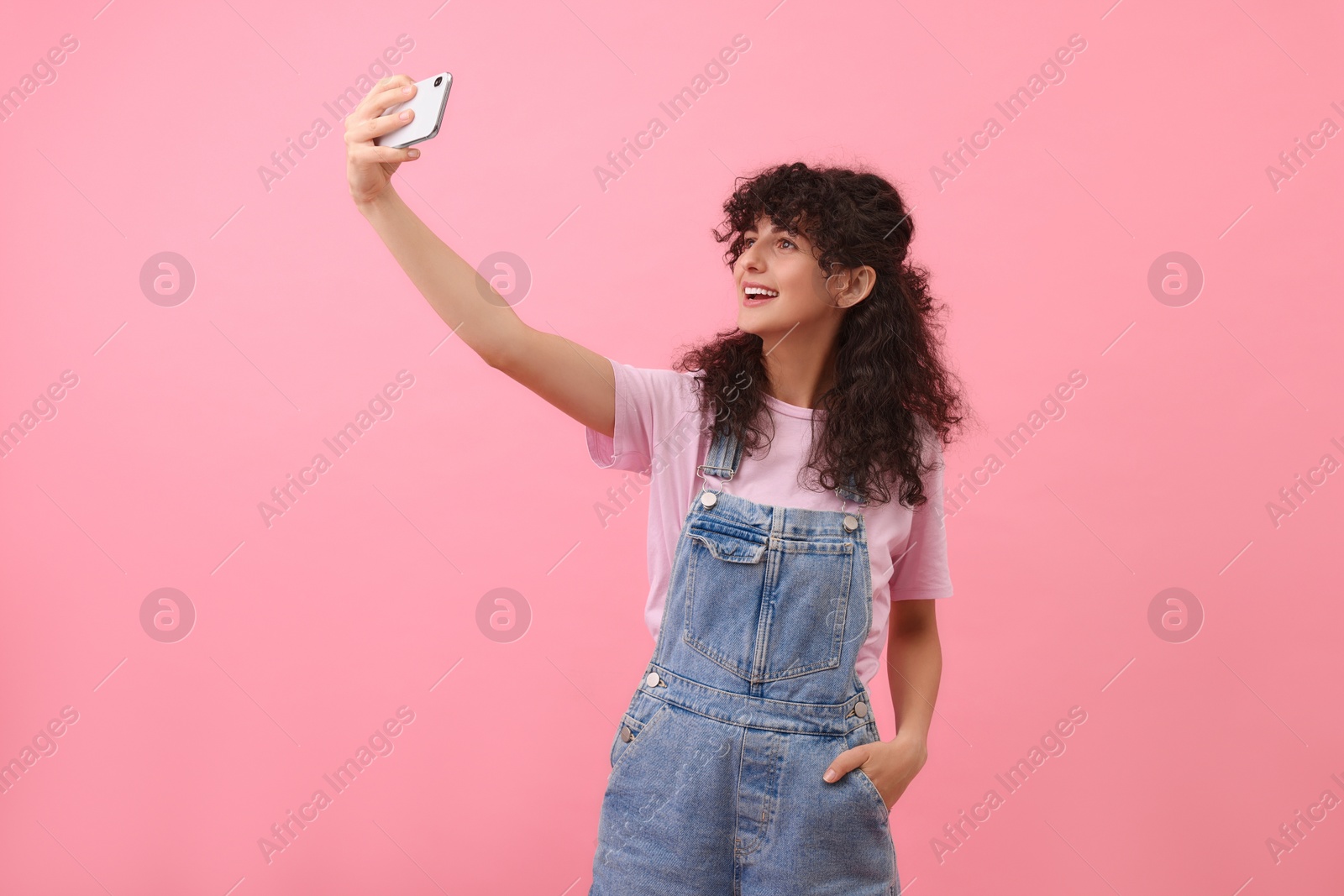 Photo of Beautiful young woman taking selfie on pink background