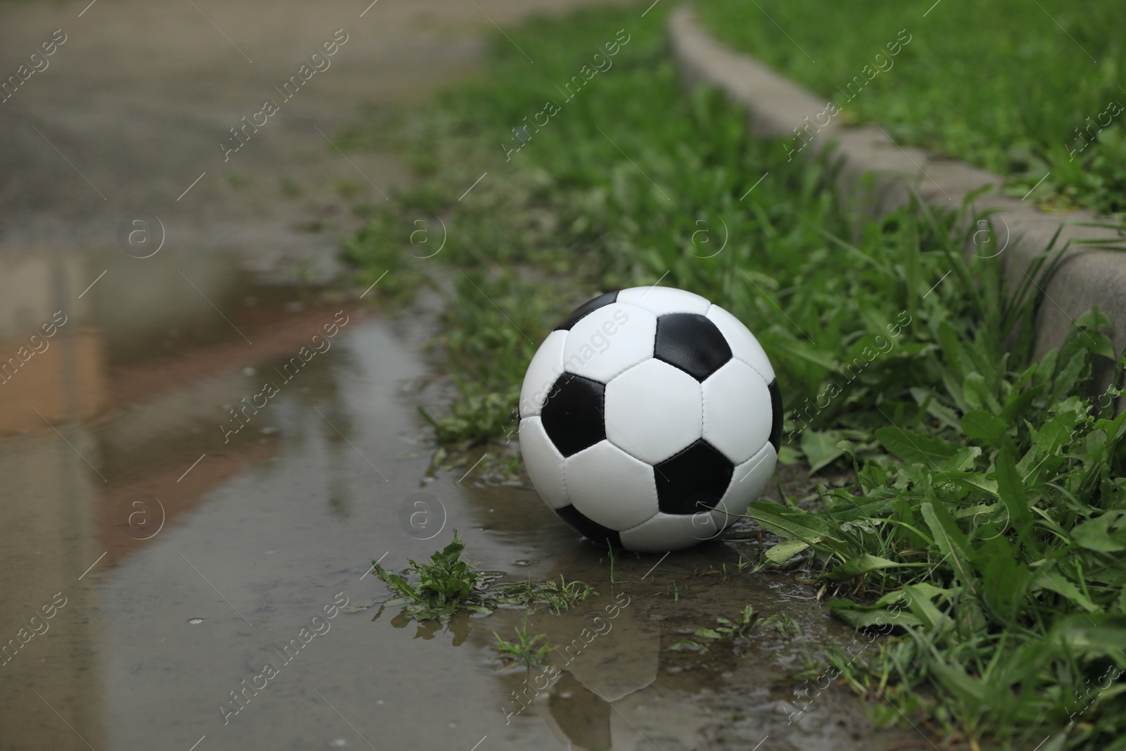 Photo of Soccer ball in puddle outdoors, space for text