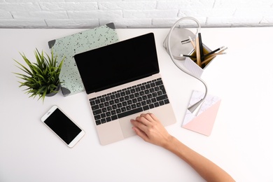 Woman using with laptop at table, top view. Mockup for design