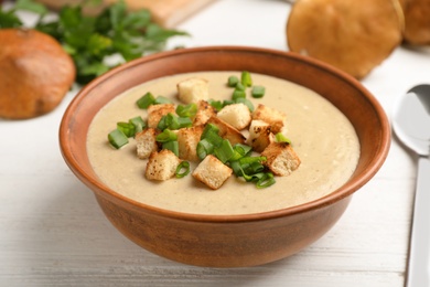 Photo of Bowl of fresh homemade mushroom soup on wooden table