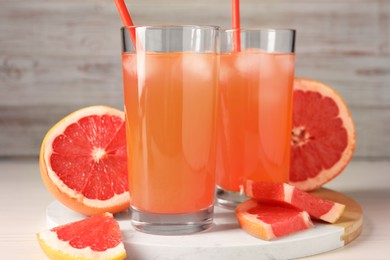 Photo of Tasty freshly made grapefruit juice and fruits on white table, closeup