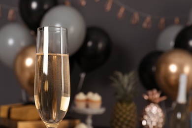 Photo of Glass of champagne and blurred balloons on background. Space for text
