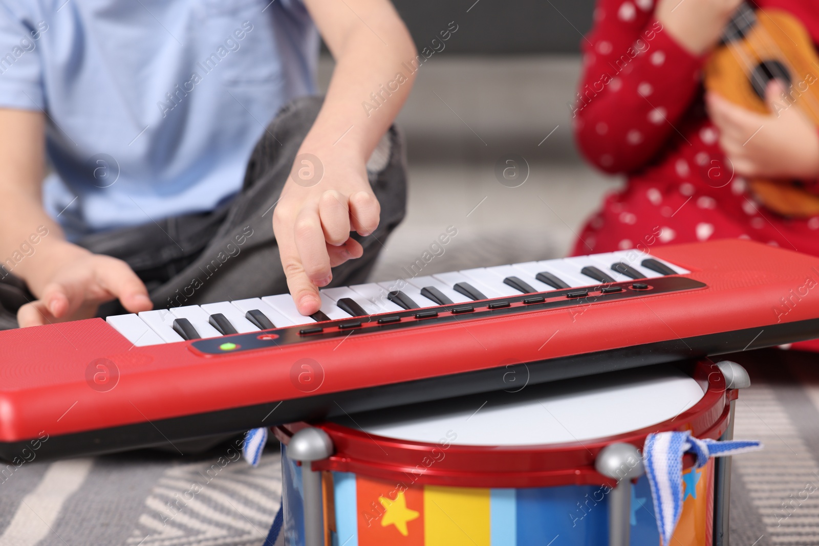Photo of Little children playing toy musical instruments at home, closeup