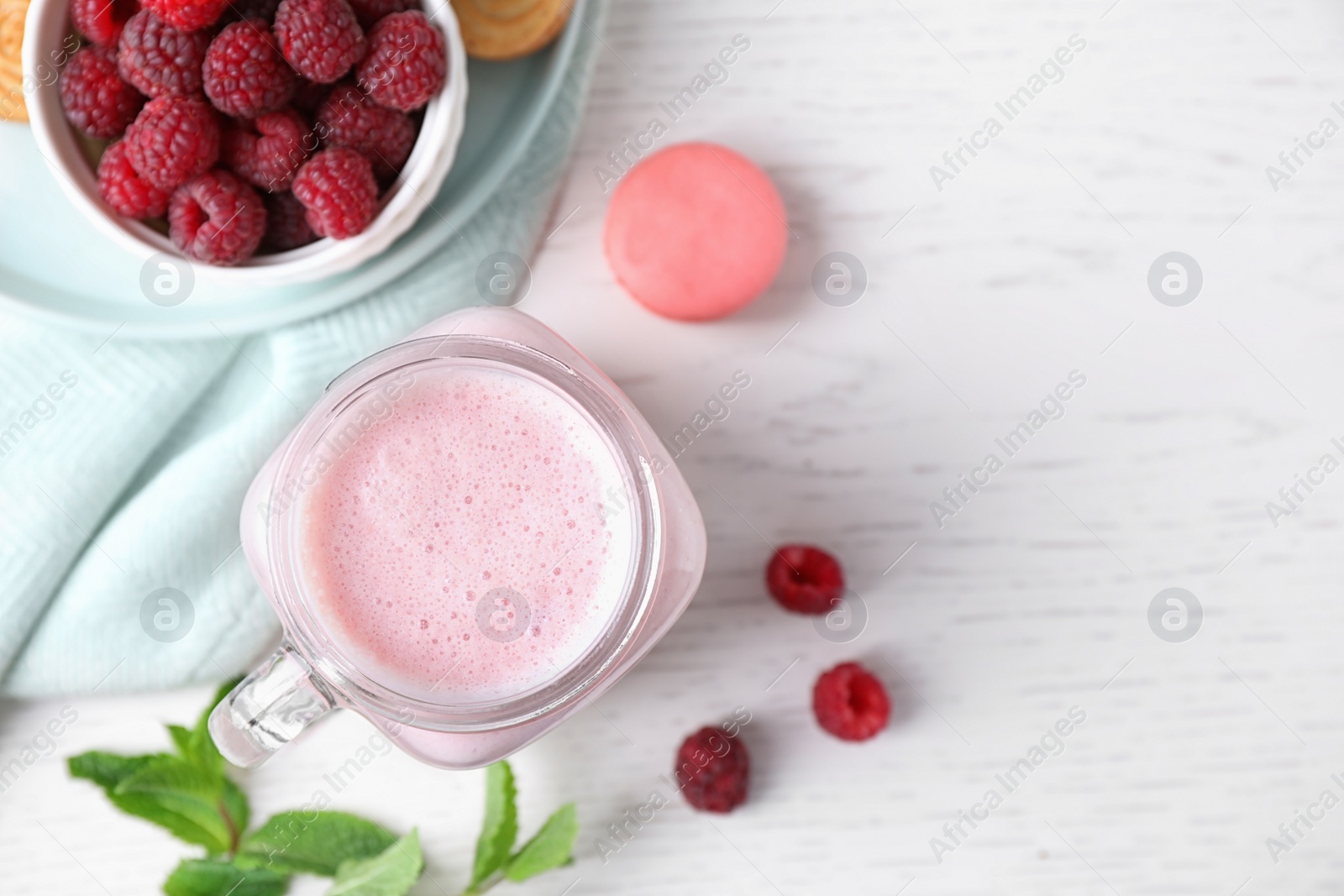 Photo of Flat lay composition with tasty raspberry milk shake on white wooden table. Space for text