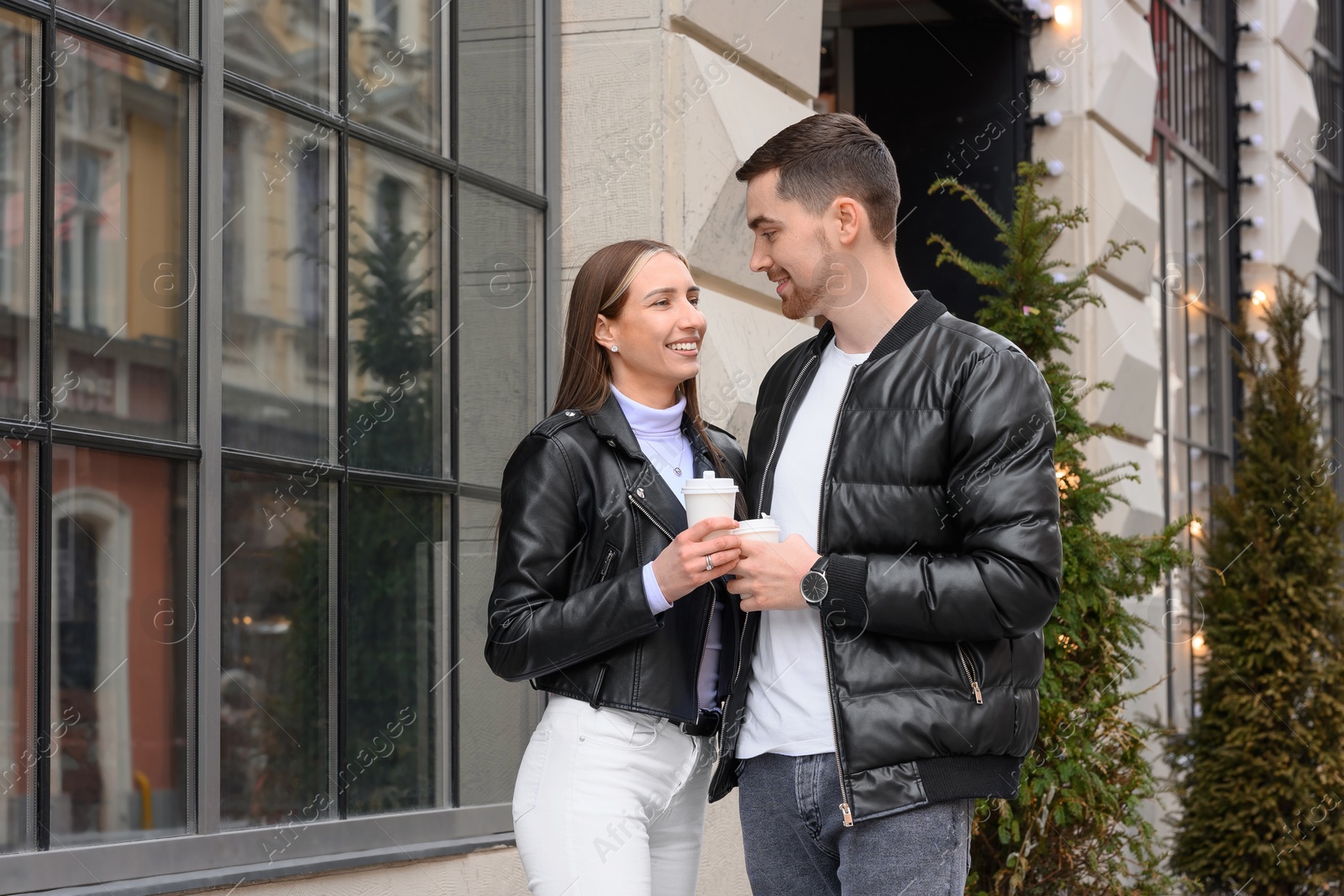 Photo of Lovely young couple with cups of coffee enjoying time together outdoors. Romantic date