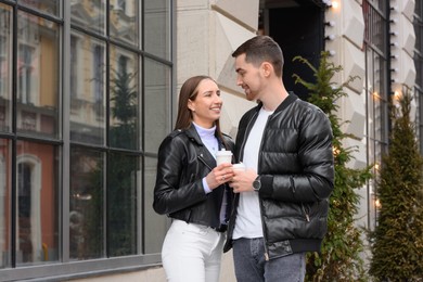 Photo of Lovely young couple with cups of coffee enjoying time together outdoors. Romantic date