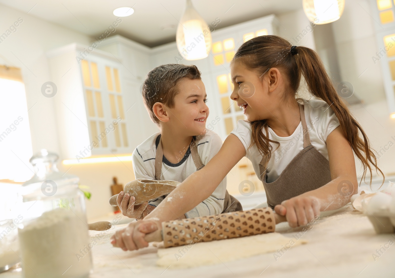 Photo of Cute little children cooking dough together in kitchen