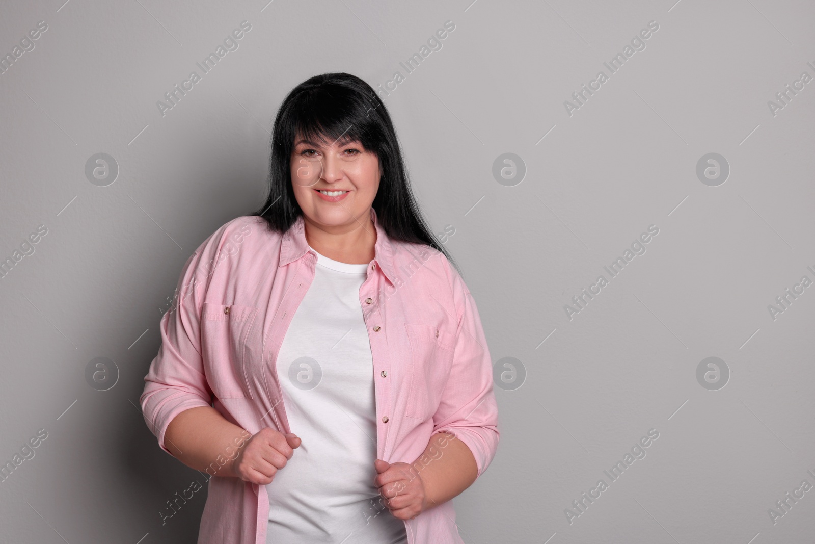 Photo of Beautiful overweight mature woman with charming smile on light grey background. Space for text