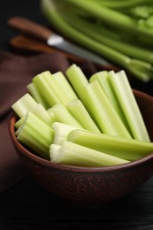 Photo of Wooden bowl of fresh cut celery on table, closeup