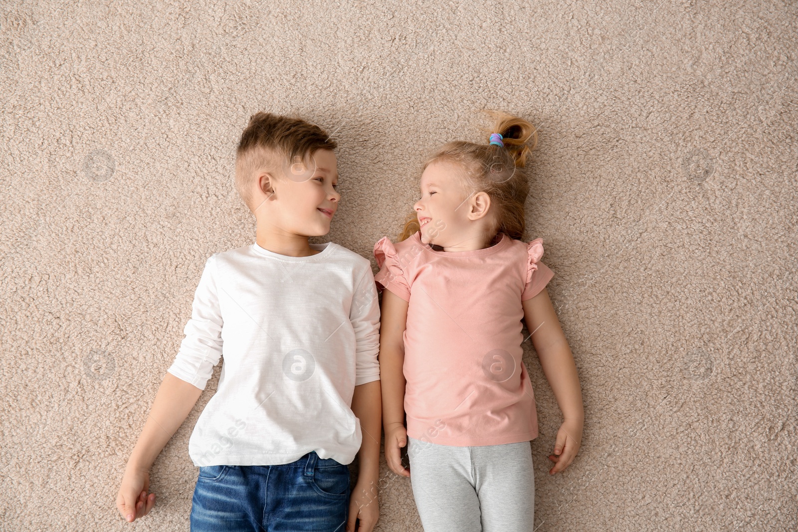 Photo of Cute little children lying on cozy carpet at home, top view