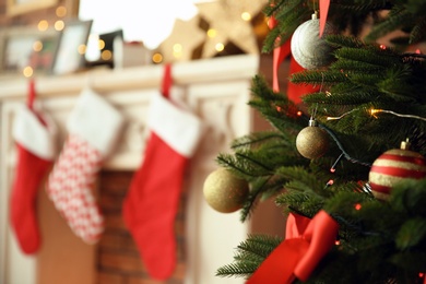 Photo of Beautiful Christmas tree near fireplace with stockings indoors, closeup