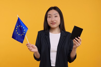 Photo of Immigration to European Union. Happy woman with passport and flag on orange background