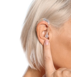 Photo of Mature woman adjusting hearing aid on white background, closeup