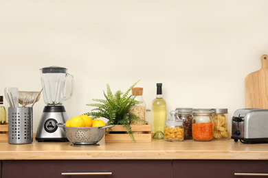 Photo of Wooden countertop with appliances and products near white wall. Kitchen interior idea