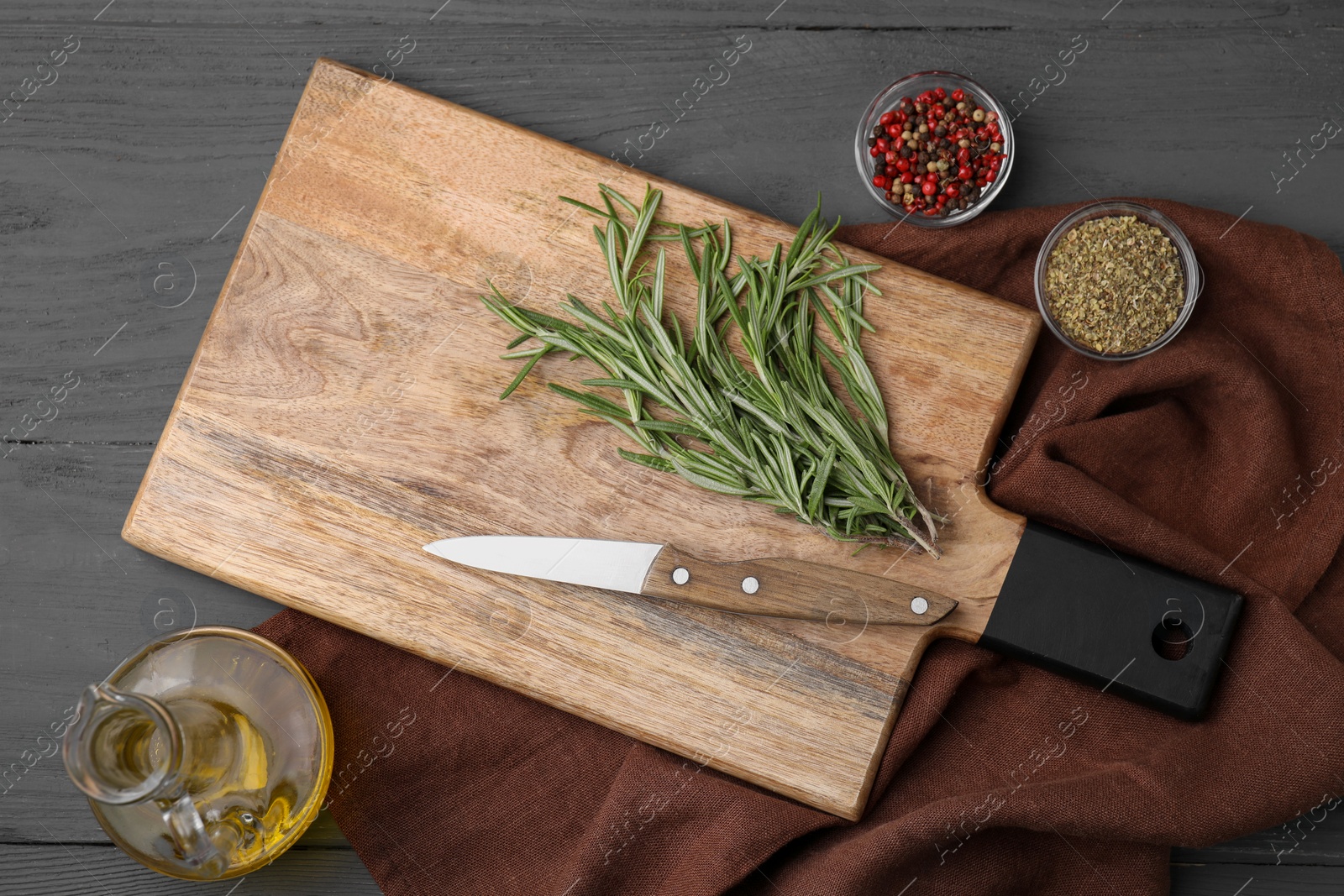 Photo of Wooden board, knife and spices on grey table, flat lay