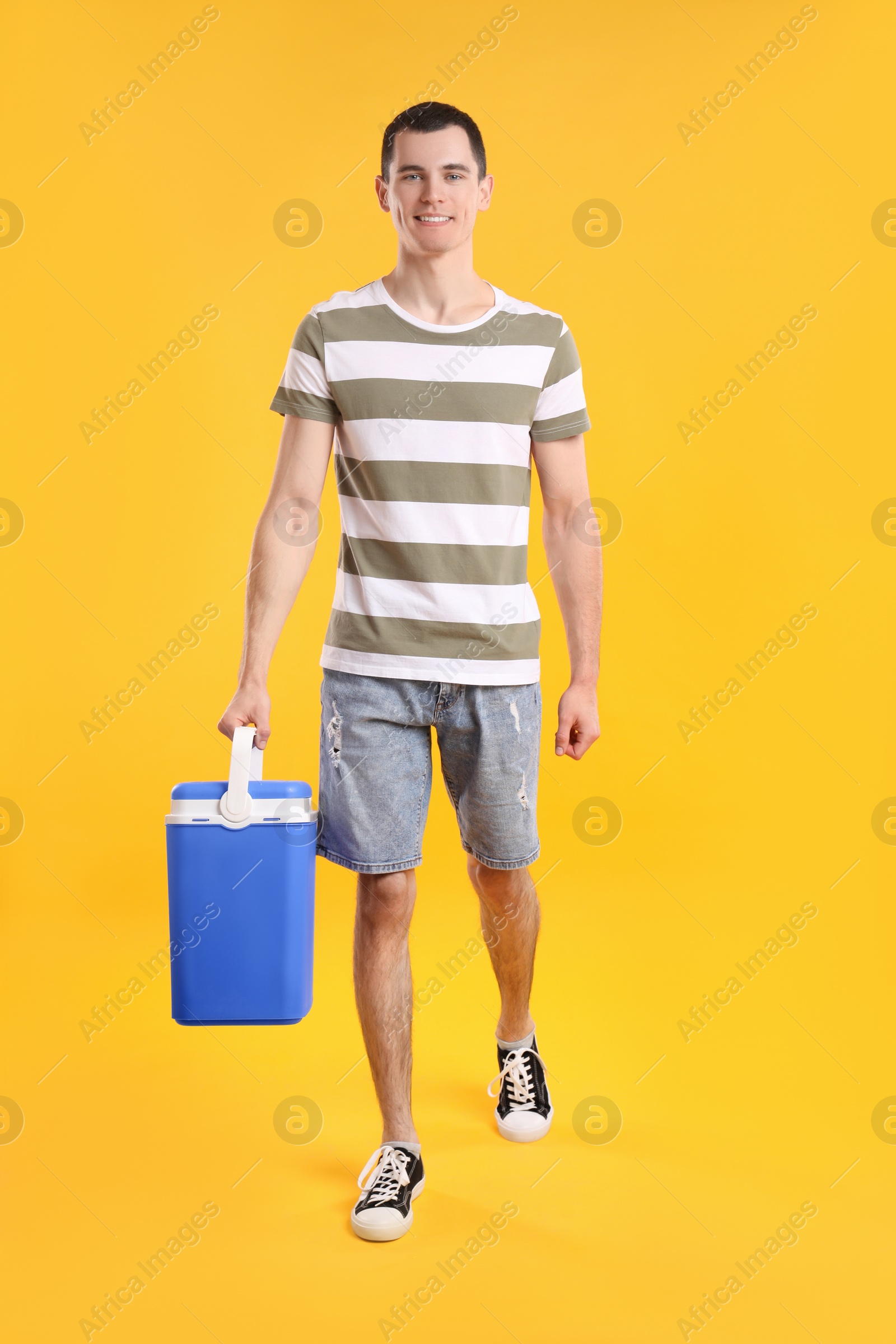 Photo of Man with blue cool box walking on orange background