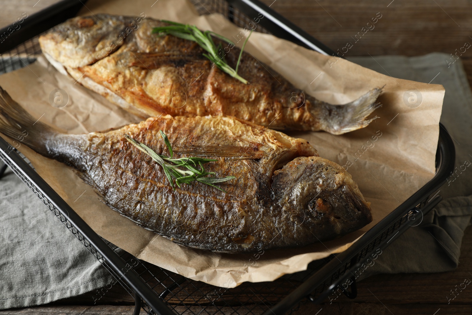 Photo of Delicious dorado fish with rosemary on wooden table, closeup