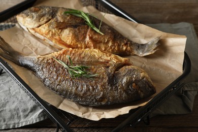 Photo of Delicious dorado fish with rosemary on wooden table, closeup