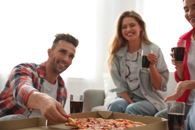 Group of friends eating tasty pizza at home