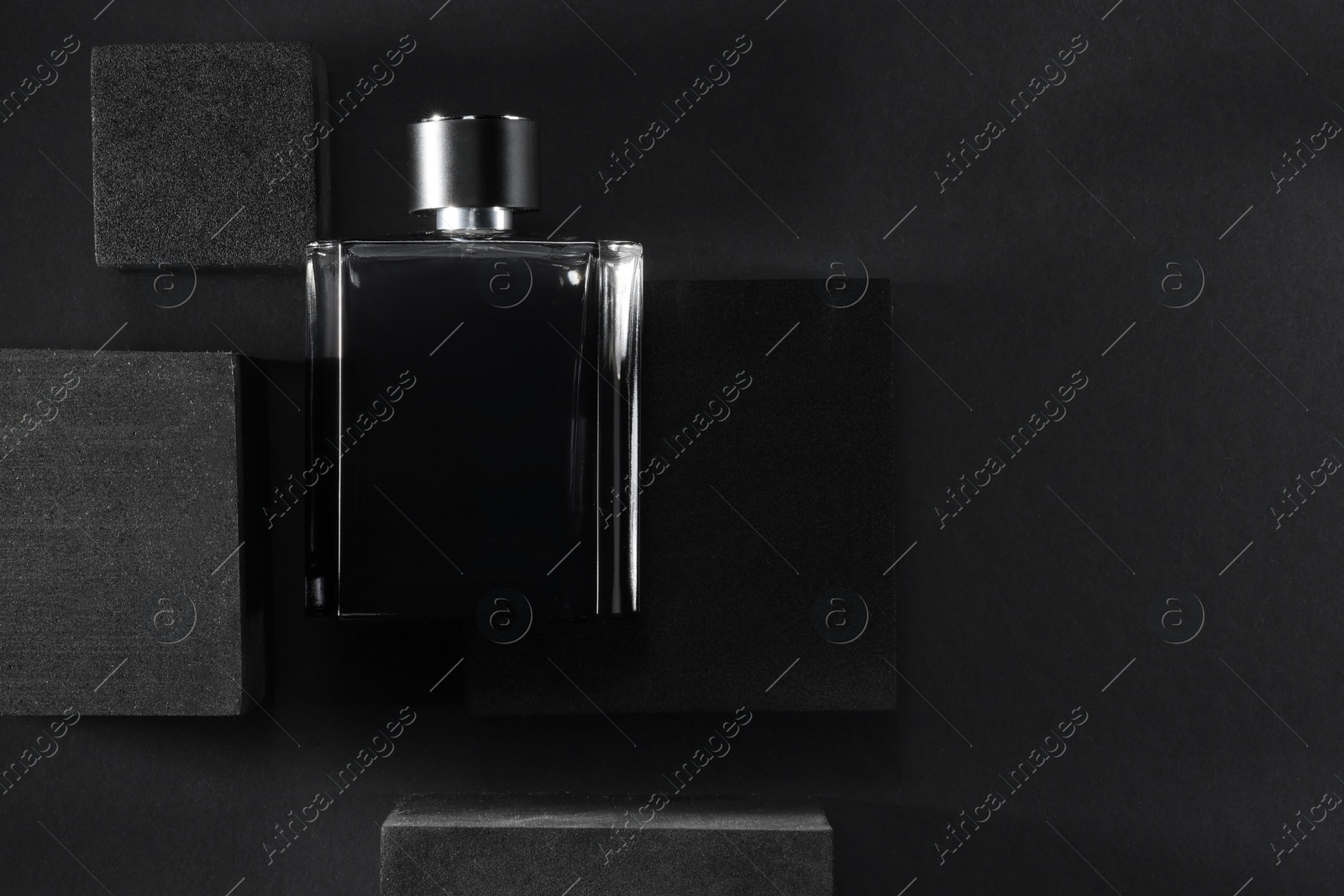 Photo of Stylish presentation of luxury men`s perfume in bottle on black background, top view. Space for text