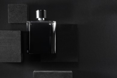 Photo of Stylish presentation of luxury men`s perfume in bottle on black background, top view. Space for text