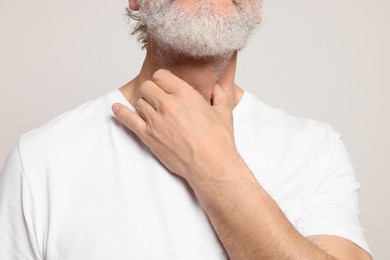 Photo of Senior man suffering from sore throat on white background, closeup. Cold symptoms