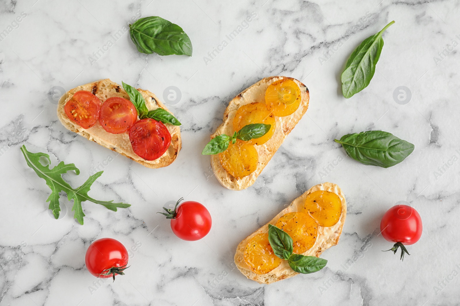 Photo of Delicious tomato bruschettas on white marble background, flat lay