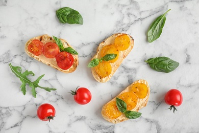 Photo of Delicious tomato bruschettas on white marble background, flat lay